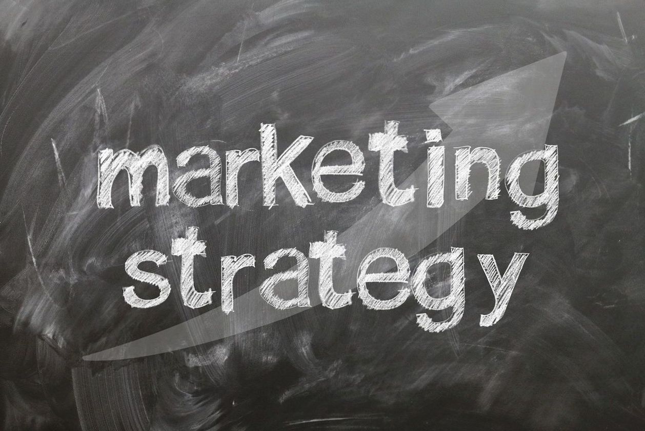Marketing strategy written on a chalkboard with an upward arrow